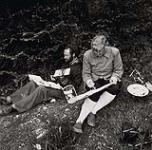 [Bearded man and Phyllis Munday seated on the grass painting] [between 1953-1964]
