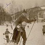[Dr. Guy Lafhambase holding a child wearing skis in his arms] [between 1953-1964]