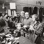 [A man, woman, and young boy, stand at the check-out counter at a ski equipment gear-swap] [between 1953-1964]