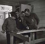 [Maurice Outhet teaching three young boys how to wax cross-country skis and talks to them about cross-country skiing techniques] [between 1953-1964]