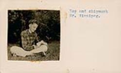 [Teen-age boy seated in the grass feeding a chipmunk] [between 1954-1963]