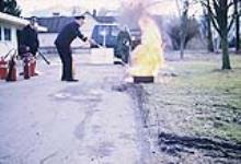 Fire marshal using a fire extinguisher to put out a tire fire février 1972