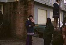 Groupe portant des parkas debout à l'extérieur d'un bâtiment de briques mars 1972