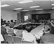 Groupe d'hommes et de femmes assis à des tables lors d'un séminaire d'une conférence sur les soins infirmiers, Ottawa 1970