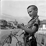 Boy playing with a toy gun, Flin Flon, Manitoba 28 juin 1956.