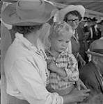 Cow-girl tenant un enfant dans ses bras, stampede, William Lake, Colombie-Britannique [ca1954-1963]