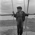 Garçon debout sur une balançoire, Swan River, Manitoba 23 juin 1956.