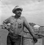 Homme debout près d'un baril [ca.1954-1963]