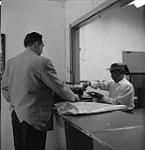 Man assisting another man at a desk [ca1954-1963]