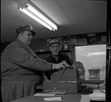 Homme portant un chapeau Esso au tiroir-caisse [ca1954-1963]