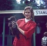 Close-up portrait of woman wearing a red shirt holding a bear cub. Children's Zoo, Stanley Park 1954