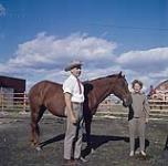 Un homme en cravate rouge et une femme, debout avec un cheval 1952