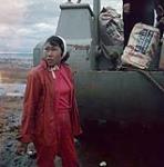 Woman [Tikisa (Mikijuk) Takpannie] participating in the unloading of an Hudson Bay Company barge at Apex, Frobisher Bay, N.W.T., [Iqaluit (formerly Frobisher Bay), Nunavut] [between June-September, 1960].