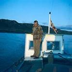 Elderly man on a boat flying a British flag. Arctic, Northern Canada [between June 17-October 31, 1960].