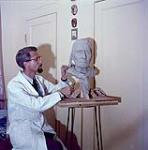 Harold Pfeiffer working on a sculpture [1955].