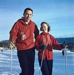 Jeune homme et femme, tous deux habillés de rouge, en train de faire du ski. Collège préuniversitaire Neuchâtel, en Suisse [1956].