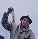 Un pêcheur montre le premier calmar de la saison, pêché près de Carbonear, Terre-Neuve. Le calmar est très prisé comme appât pour la morue [Un pêcheur montre le premier calmar de la saison, pêché près de Carbonear, Terre-Neuve. Le calmar est très prisé comme appât pour la morue.] août 1960