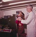 Susan Kelloway being x-rayed by technician Hubert Stokes aboard the M.V. Christmas Seal. Newfoundland. August 1960
