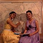 [Two women sitting in front of a world map] June 1956