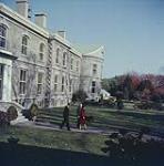 H.M. Queen Elizabeth II and H.R.H. Prince Philip, the Duke of Edinburgh, accompanied by H.E., the Governor General, Vincent Massey and the dog, Duff, strolling in the gardens of Rideau Hall, Oct. 15, 1957. Ottawa, Ont.  15 octobre 1957.