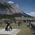 Queen Elizabeth and Prince Philip at the Royal Canadian Army Cadet National Camp, watching two men wrestle. Banff, Alberta.  July 1959