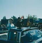 Queen Elizabeth and Prince Philip riding in a convertible through Vernon, B.C.  [La reine Élizabeth et le prince Philip debout en voiture saluant la foule au cours d'une visite royale à Vernon en Colombie-Britannique] juillet 1959