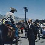 Queen Elizabeth and Prince Philip's arrival at Kamloops, B.C., horses from the local ranch were ridden down to the station to form a Guard of Honor. Prince Philip talks with one of the riders.  July 1959