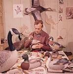 Jean Marc Deschenes painting bird figures in his studio at St. Jean Port Joli, P.Q. June 1959