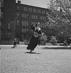 Religieuse jouant au tennis pendant que des enfants la regardent au passage au couvent Notre-Dame, Sherbrooke, 1957 1957