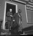 Père Tompkuis - Femme quittant l'édifice et homme non identifié dans l'embrasure de la porte août 1940