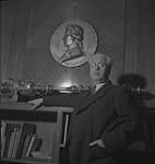 Vancouver.  J. Lyle Telford Standing Beside Bookshelf [entre 1939-1951]