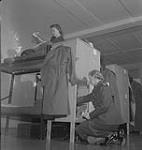 Hôpital Women's College. Femme non identifiée en uniforme agenouillée devant un placard [entre 1939-1951]