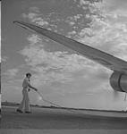 Winnipeg, années 1940. Un pilote non identifié tire une corde sur une aile d'avion [entre 1940-1949]