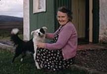 Woman wearing a pink sweater with a dog [ca. 1953-1964]
