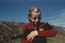 Jeune fille portant gilet rouge et tenant un chat noir [ca. 1953-1964]