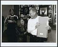 BMG Canada President Paul Alofs plays hide & seek with Deborah Cox's first ever gold record. From left to right: Lascelles Stephens, Deborah Cox, Paul Alofs [entre 1996-1997].