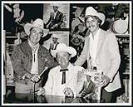 Lors de sa séance d'autographes au Eatons de Calgary, Wilf Carter en compagnie de Don Slade de CFCN et de Terry Carson de RCA [ca. 1983]