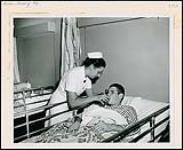 A nurse give a male patient a drink. Nurses and Nursing. Department of Citizenship and Immigration, Information Division [between 1930-1960]