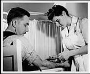 A nurse giving a needle to a seated man. National Film Board of Canada. Industrial Nursing. Department of Citizenship and Immigration, Information Division [between 1930-1960]