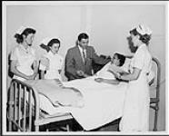 Trois infirmières et un médecin dans une chambre d'hôpital durant une clinique de soins infirmiers. St. Joseph Hospital, Victoria. Infirmières et soins. Ministère de la Citoyenneté et de l'Immigration, division de l'information [entre 1930-1960]