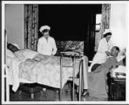 Deux infirmières prodiguant des soins à deux patients. Salle médicale Mews, St. Joseph Hospital, Victoria. Infirmières et soins. Ministère de la Citoyenneté et de l'Immigration, division de l'information [entre 1930-1960]