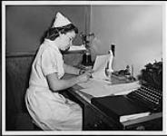 A nurse filling out a patient report. Children's ward, St. Joseph's Hospital, Victoria. Nurses and Nursing. Department of Citizenship and Immigration, Information Division [between 1930-1960]