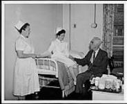 A Professinal Student Nurse tends to a patient in bed with the help of a supervisor. Edmonton. Nurses and Nursing. Department of Citizenship and Immigration, Information Division [entre 1930-1960]