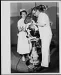 Dentiste réparant les dents d'un jeune patient. Infirmière à ses côtés. Hospital for Sick Children, Toronto. Ministère de la Citoyenneté et de l'Immigration, division de l'information [entre 1930-1960]