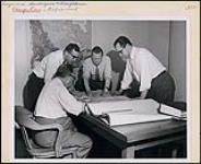 A group of engineers working together in one of Canada's large engineering firms confer over the plans for a complex development project. Occupations - Professional Engineers. Department of Citizenship and Immigration, Information Division [entre 1930-1960]