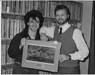 L'artiste de studio d'enregistrement Gowan de Columbia remet à Greg Simpson, directeur musical du FM 96 de Londres, une lithographie encadrée en remerciement de l'appui de sa station à l'album Strange Animal (qui a atteint le niveau Or au Canada) [ca 1985].