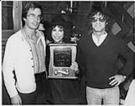J. Robert Wood (Program Director, CHUM-FM), Carolyne Mas (American recording artist) and Gerry Young (Promotion Director, PolyGram) holding a Bone of the Year Award [ca 1979]