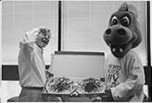 Bmg Music Canada President Paul Alofs tucks into a tasty worm compliments of Gary Slaight. Slaight sent BMG a couple of pizzas complete with live worm topping as a thank you to the staff for the job they did in promoting the new Crash Test Dummies album A Worm's Life [ca. 1996]