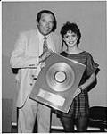 David Evans, président d'EMI Canada remettant à Sheena Easton un disque d'or pour son disque longue durée Madness, Money & Music, après un concert à guichets fermés au Roy Thomson Hall de Toronto [ca 1980]
