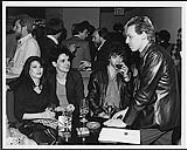 Le chanteur du groupe Glamatron, Rudy Van Steenes, bavarde avec des membres du groupe Sylum à la fête donnée en l'honneur du premier anniversaire du groupe Factor's. Les deux groupes étaient parmi cinquante candidats ayant reçu des prêts pour une production de disque en 1982-1983 1983